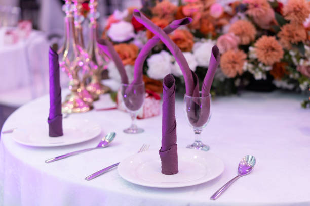 Table setup with folded napkin on a plate, wine glass, and spoon and fork on the side. Dinner table set up concept.