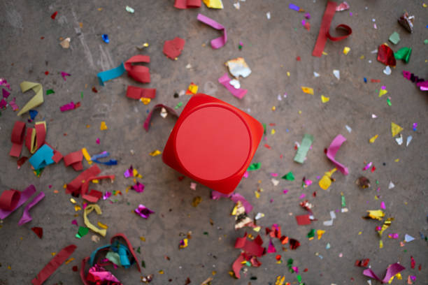 Red dice placed on the floor, surrounded by multicolored confetti made from ecological recycled paper.