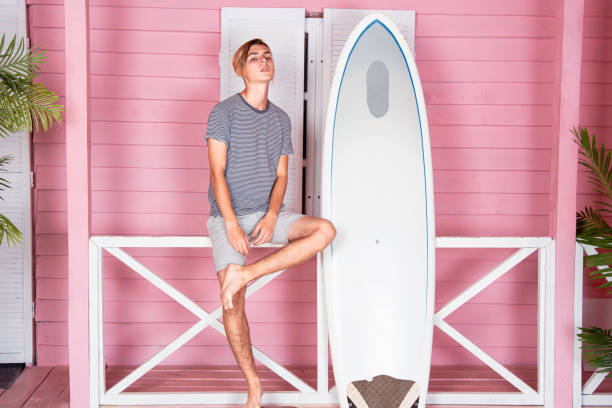 istock Vacation at sea. Young attractive guy on the beach with a surfboard. 2170774961