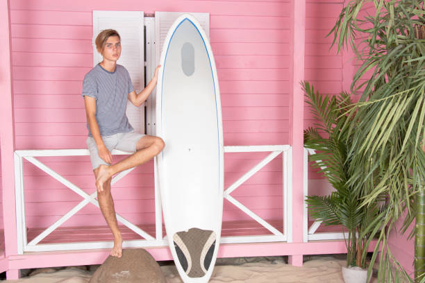 istock Vacation at sea. Young attractive guy on the beach with a surfboard. 2170775435