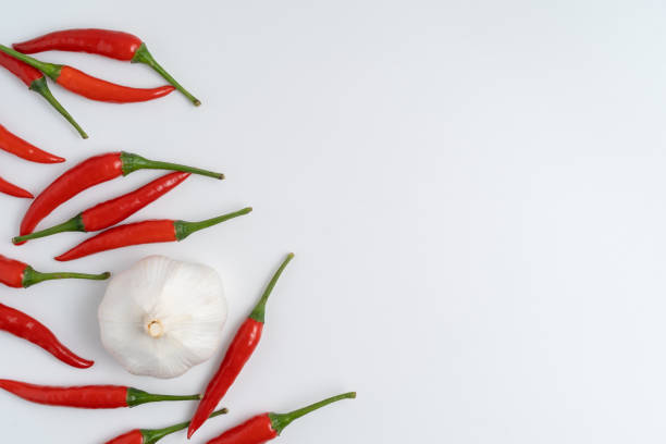 Layflat composition featuring vibrant red chili peppers and garlic with a copy space against a clean, white backdrop.