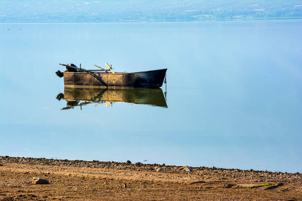 A single boat rests calmly on the still waters of Lake Kerkini, Greece, with a perfect reflection creating a serene and peaceful scene.