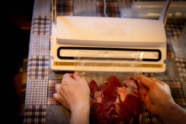 Hand of a woman vacuum packing fresh beef meat for the freezer.