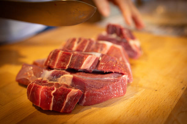Fresh beef steaks set on a wooden cutting board in the kitchen.