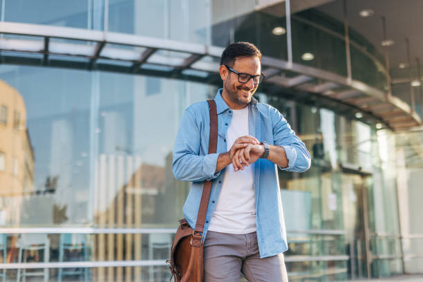 istock A handsome, cheerful, smiling man walking by a building, carrying bag. 2170785271