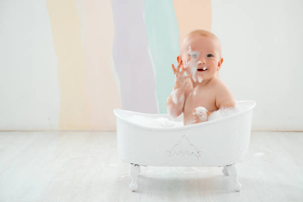 a baby boy is bathing in a bubble bath, a small child is playing with foam and splashes having fun and laughing, foam in front of the child