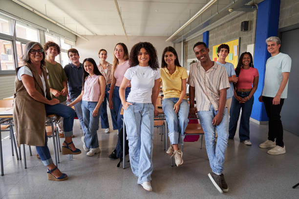 Cheerful group of high school students in classroom, looking at camera smiling.