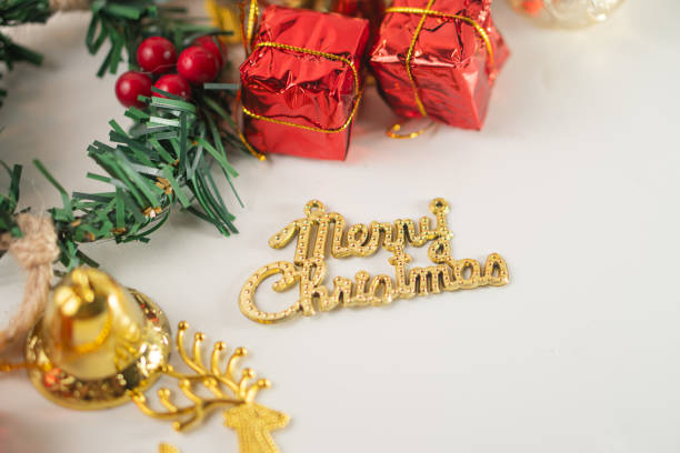A festive arrangement of Christmas decorations including colorful baubles, small gift boxes, a golden reindeer, and a merry Christmas sign on a white background.