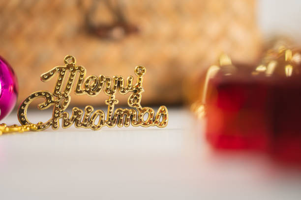 A festive arrangement featuring a woven basket adorned with greenery, colorful Christmas ornaments, golden bells, and small wrapped gifts. The scene conveys a cheerful holiday spirit.