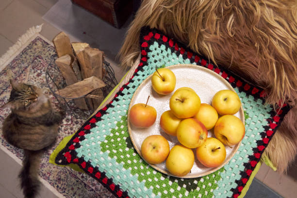 still life with yellow apples on a plate that stands on a knitted cushion, top view