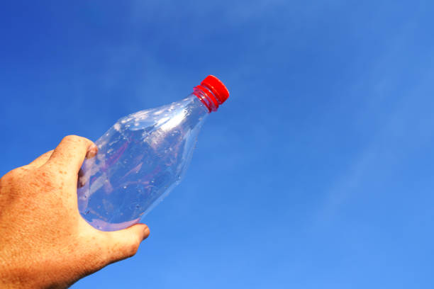istock Plastic bottle in hand on blue sky background. Plastic recycling and waste collection. 2170815440