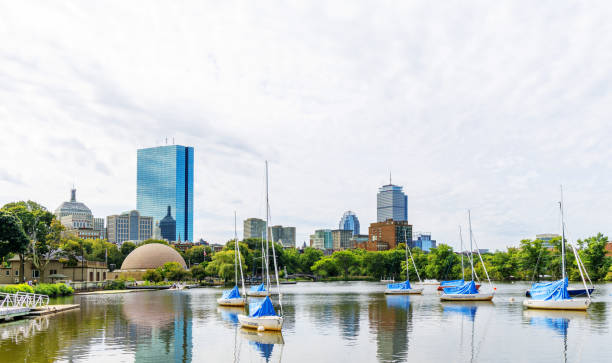 Boston, Massachusetts, USA - September 2, 2024:  The Boston Back Bay skyline as seen across the Charles River Esplanade.  A community boating marina is in the foreground. Also visible is the Hatch Memorial Shell on the Esplanade and the John Hancock and Prudential Center Towers.