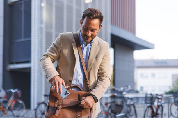 istock Man placing phone in leather bag, ready for work. 2170817595