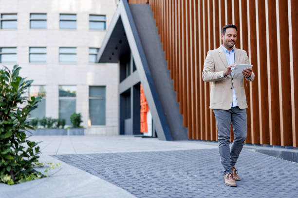 istock Man with tablet walking on paved outdoor area 2170817748