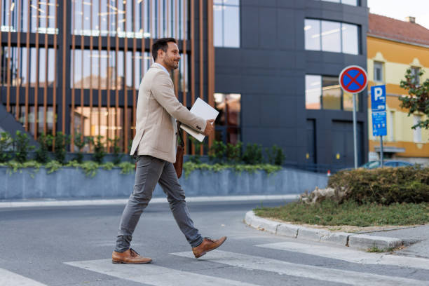 istock Man walking on crosswalk holding laptop near office 2170817859
