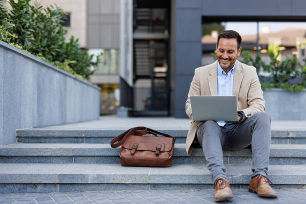 istock Engaged man working on laptop sitting on urban stairs 2170818550