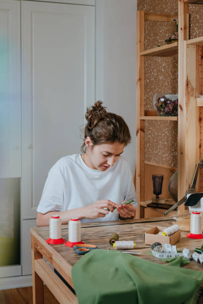 istock Female tailor sewing sitting at the table near sewing machine 2170820408