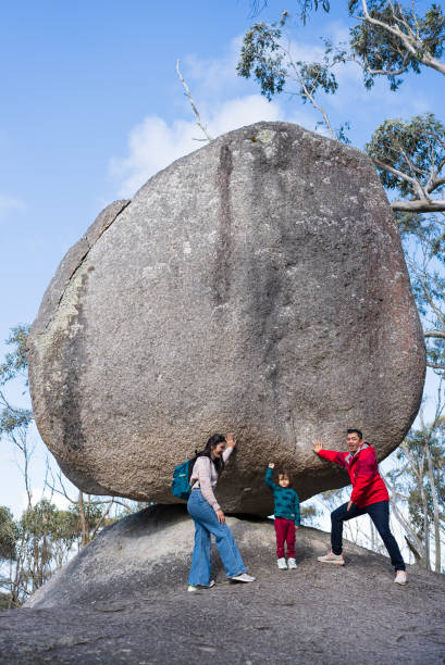 asian family resting  under a large boulder in The Granite Skywalk in Mount Gardner, Mount Manypeaks , Albany
