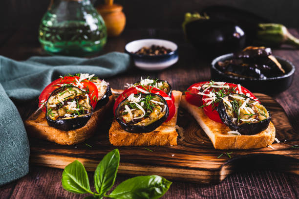 istock Fried toasts with grilled eggplant, tomatoes and cheese on a board on the table 2170829677
