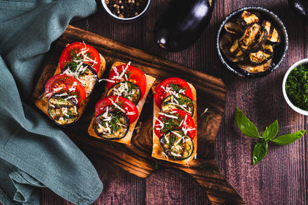 istock Fried toasts with grilled eggplant, tomatoes and cheese on a board on the table top view 2170829715