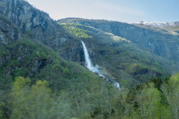 The Rjoandefossen waterfall cascades down a steep mountainside, creating a breathtaking sight for passengers aboard the Flam Railway. This powerful waterfall is a highlight of the scenic journey.