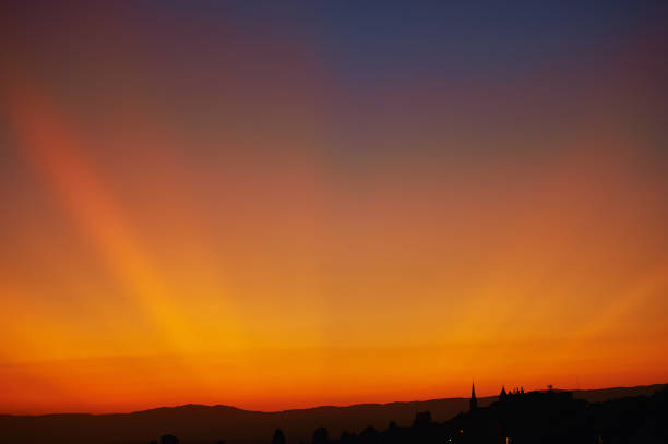 Beautiful sunset with dramatic orange yellow rays of light on dark blue sky