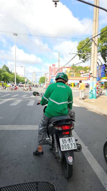 A grab motorbike taxi driver on the street at Can Tho city, Vietnam. Can Tho, Vietnam - August 15, 2024: A grab motorbike taxi driver on the street at Can Tho city, Vietnam. vietnamese man taxi motorbike driver stock pictures, royalty-free photos & images
