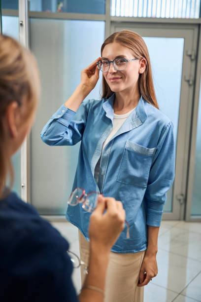 istock Woman trying on glasses, adjusting frames in front of mirror 2170836774