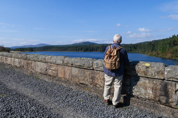 istock Senior man standing on a bridge looking at a loch 2170838623