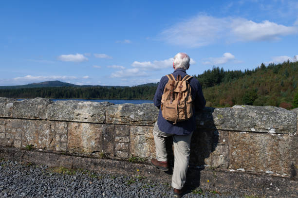 istock Retired man standing on a bridge looking at a loch 2170838654