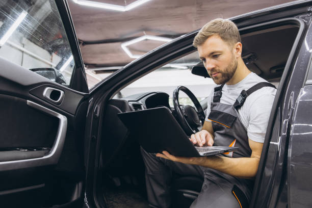istock Automotive mechanic running diagnostics software on computer. Mechanic sitting in car and working on laptop while doing vehicle diagnostic test in auto service garage. 2170840069
