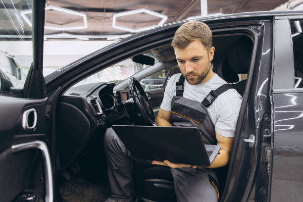istock Automotive mechanic running diagnostics software on computer. Mechanic sitting in car and working on laptop while doing vehicle diagnostic test in auto service garage. 2170840070