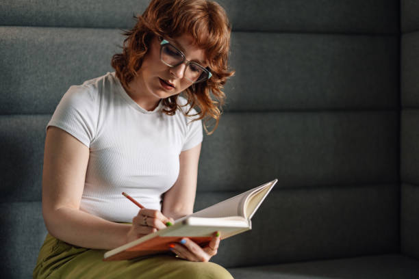 istock Focused businesswoman writing down notes in textbook at modern office. 2170844684
