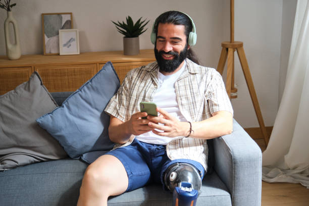 istock Smiling man with disability using smartphone and wearing headphones at home 2170845070