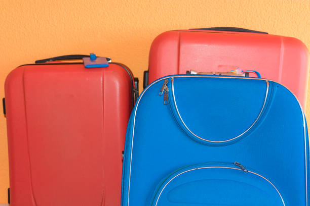 Three suitcases stand ready, perfectly packed and aligned, symbolizing the beginning of an exciting new adventure. The bright red and blue colors of the luggage capture the spirit of travel and exploration. These bags, equipped with sturdy handles and secure locks, are ideal companions for any journey, whether it be a weekend getaway or a long international trip.