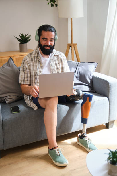 istock Smiling man with prosthetic leg using laptop on sofa at home 2170845253