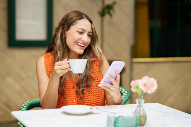 istock Latin woman smiling while using mobile phone in a cafeteria 2170845352