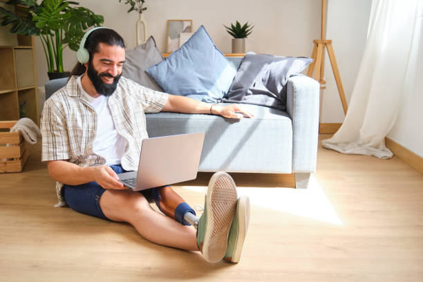 istock Smiling man with prosthetic leg using laptop at home 2170845499