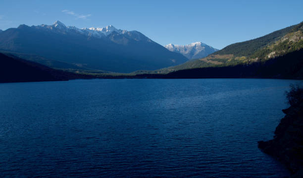 Ground-level wide shot of snowcapped mountain peaks beyond Canada's Anderson Lake