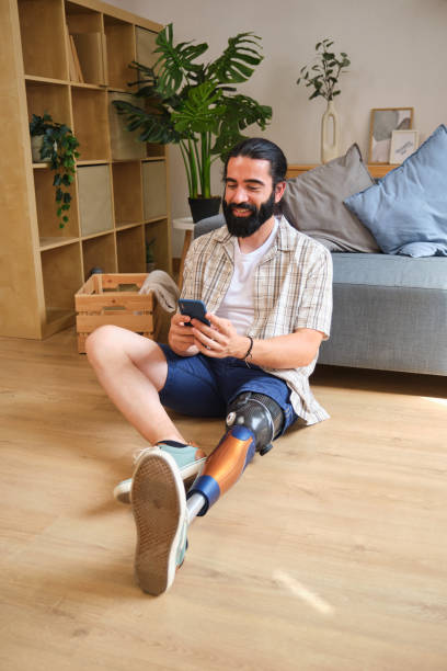 istock Smiling man with prosthetic leg using smartphone at home 2170845836