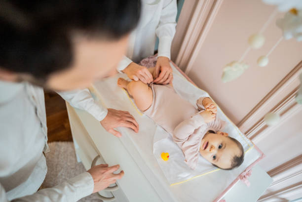 Parents changing their daughter's clothes at home