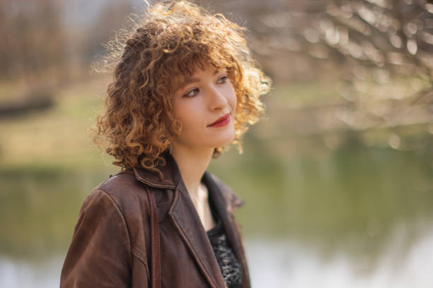Redhead curly woman in park.