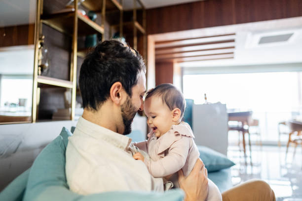 istock Father with daughter on his lap at home 2170846668