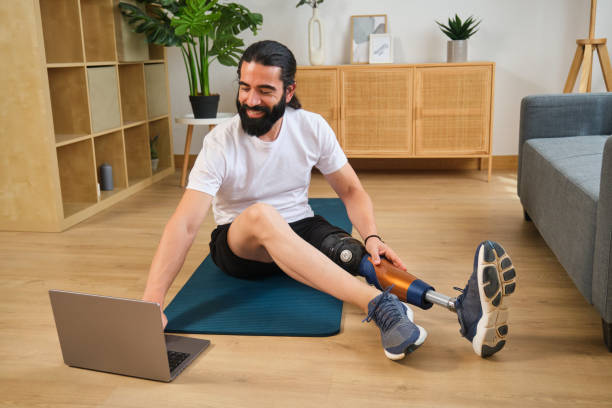istock Smiling young man with prosthetic leg doing online exercise at home 2170847539