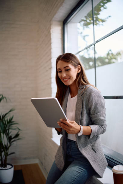 Happy female entrepreneur working on digital tablet in the office.
