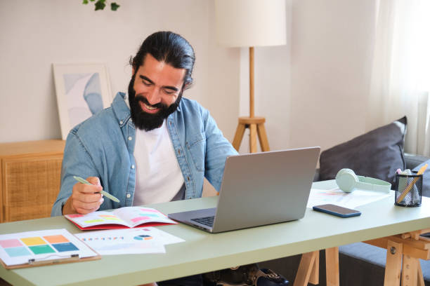 istock Happy designer working from home office taking notes smiling at laptop 2170849444