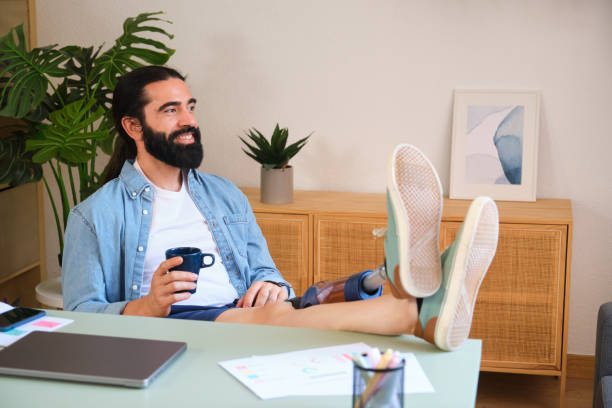 istock Young freelancer with prosthetic leg relaxing at home office drinking coffee 2170849680