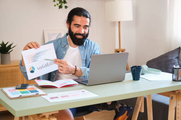 istock Young entrepreneur with disability analyzing charts on a video call at home office 2170849857
