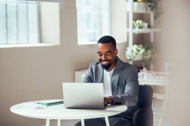 Businessman Smiling While Working on Laptop in Modern Office