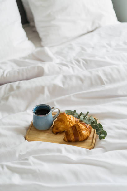 istock Breakfast tray with coffee cup and croissant on bed 2170859818
